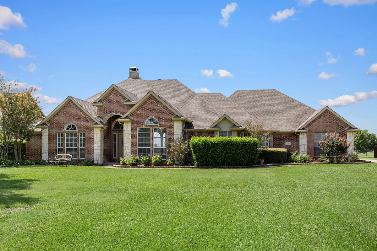 Front exterior of 9530 Blarney Stone Way, a brick home with a broad green lawn