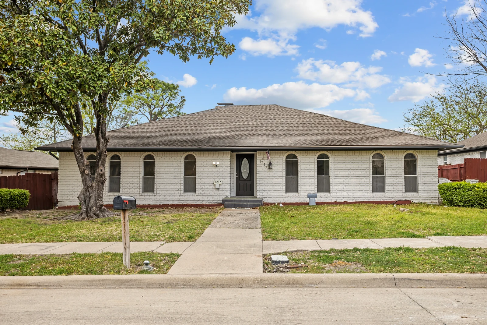 Front exterior of 1217 Pecan Valley Drive with arched windows and the entry walkway