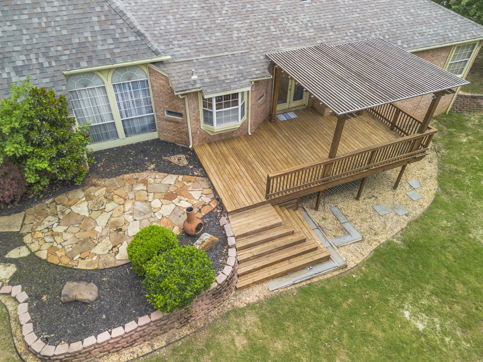 Rear aerial view of 4100 Crest Ridge Drive showing the deck, pergola and stone patio