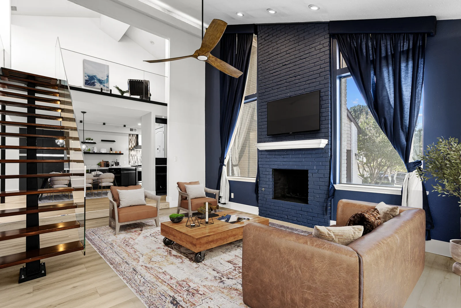 Living-room view at 4118 Crossing Lane with a brick fireplace, tall windows and open staircase