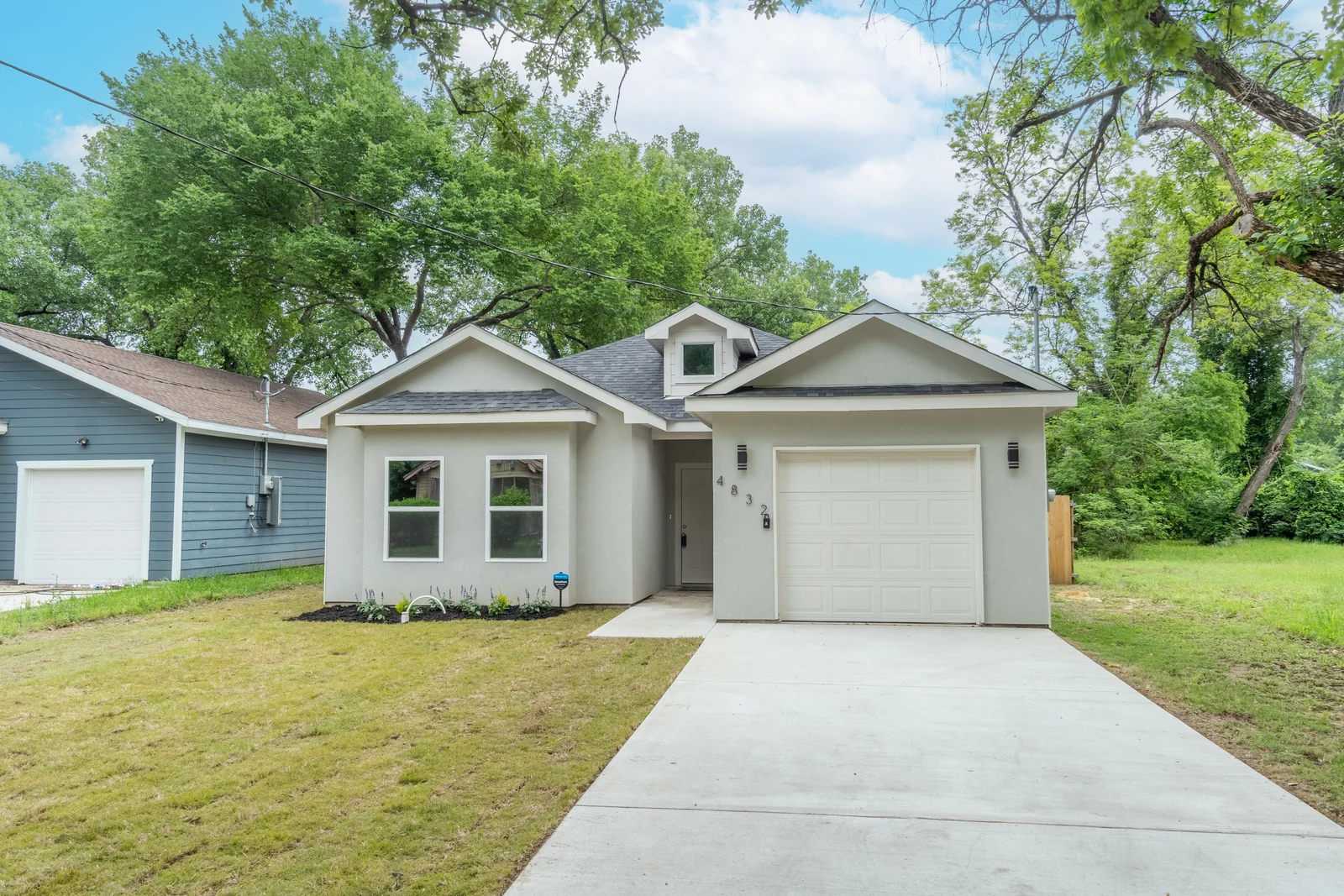 Front exterior of 4832 Nome Street with the driveway, garage and trees behind the house